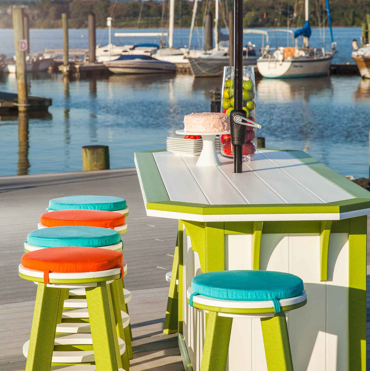 Round teal and orange cushion pads tied onto lime green poly bar stools at a marina bar table