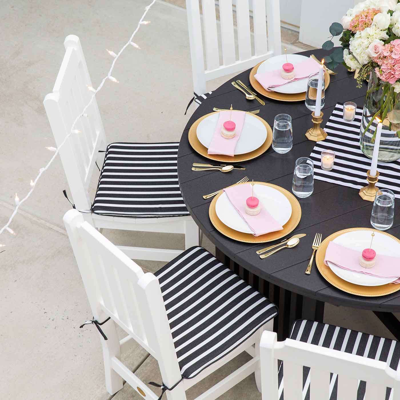 Black and white striped square seat cushions tied to white poly chairs at a set round table