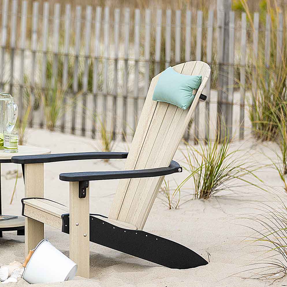 Seafoam neck pillow on the back of a driftwood poly Adirondack chair in beach dune grass