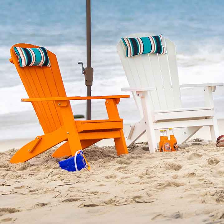 Striped neck pillows on orange and white poly Adirondack chairs facing the ocean surf
