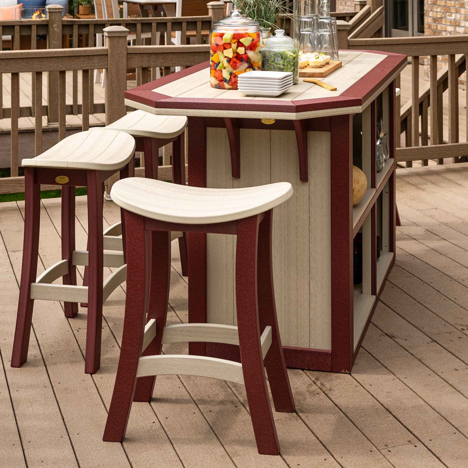 Three weatherwood and cherry saddle bar stools pulled up to a matching poly outdoor bar island on a backyard deck