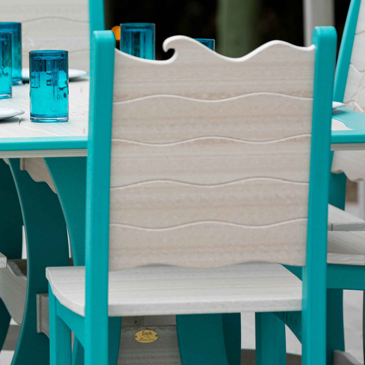 Rear view of a wave back counter chair in driftwood and aruba blue beside a set table with blue glasses