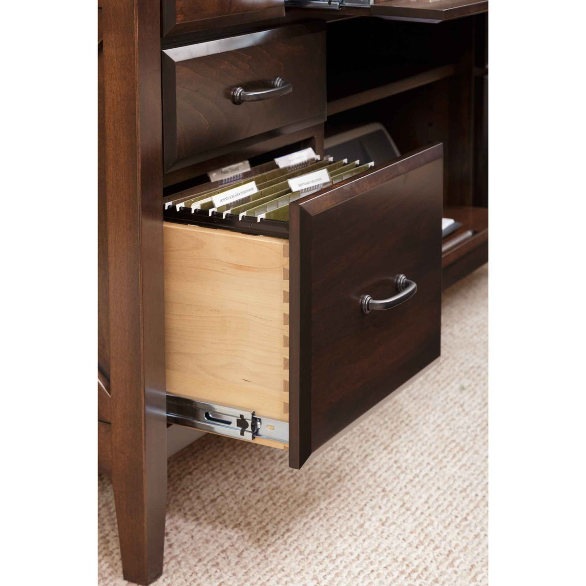 Credenza file drawer opened to labeled hanging folders inside a dovetailed maple drawer box