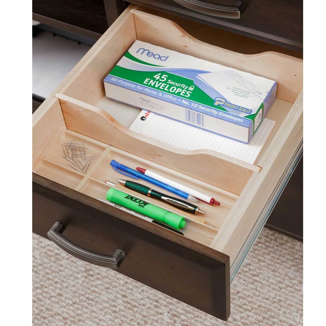 Credenza drawer opened to a maple divided tray holding envelopes, a notepad, pens and paper clips