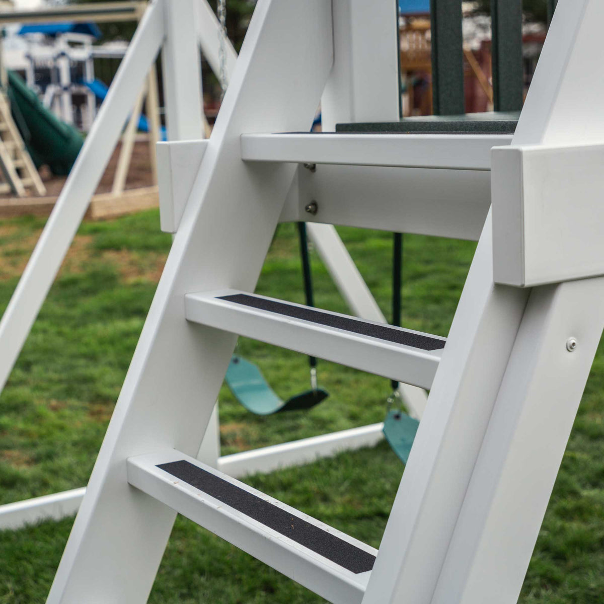 Close-up of the playset ladder steps with black no-slip tread strips and white vinyl side rails
