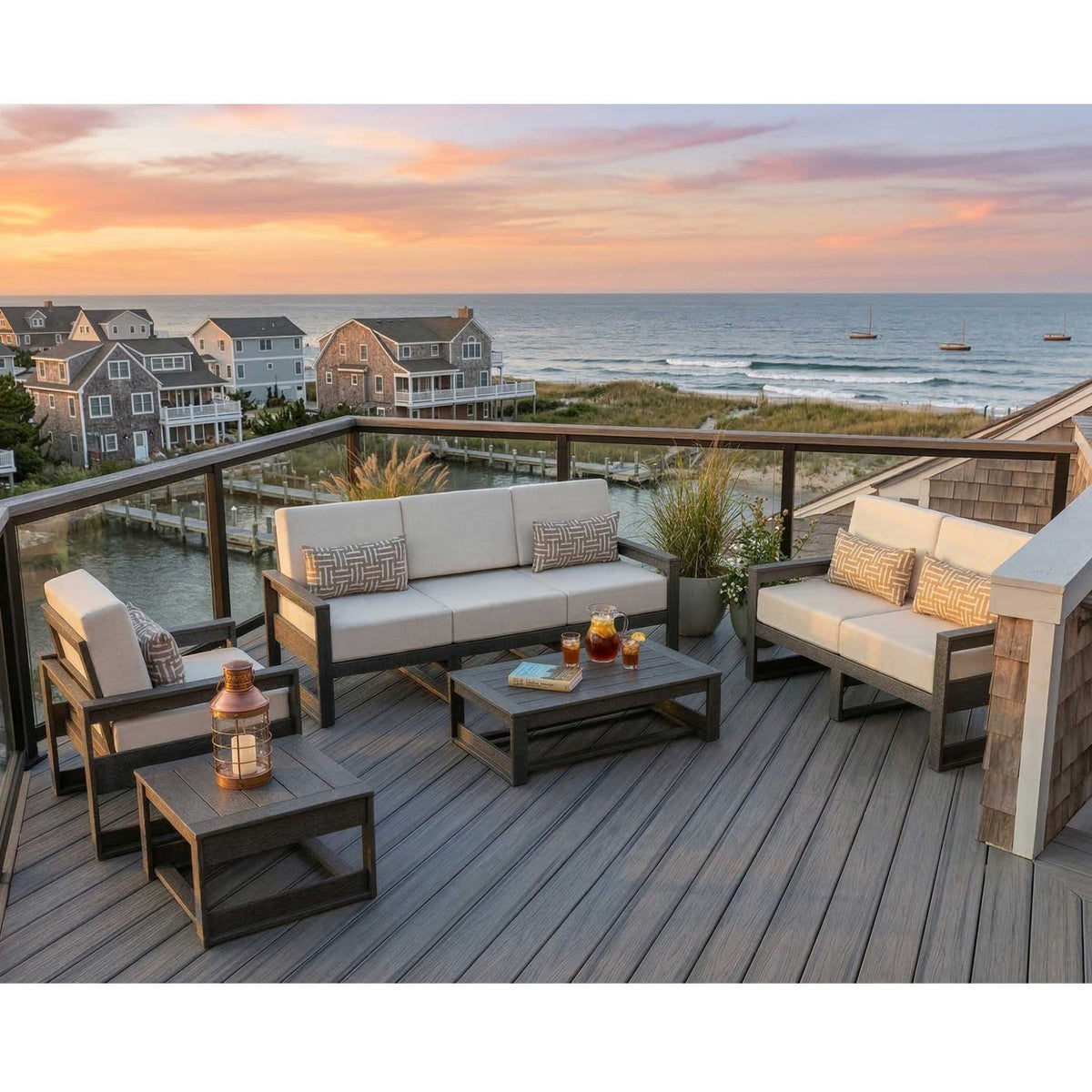 Poly patio sofa, loveseat, chair and tables with cream cushions on an oceanfront deck at sunset