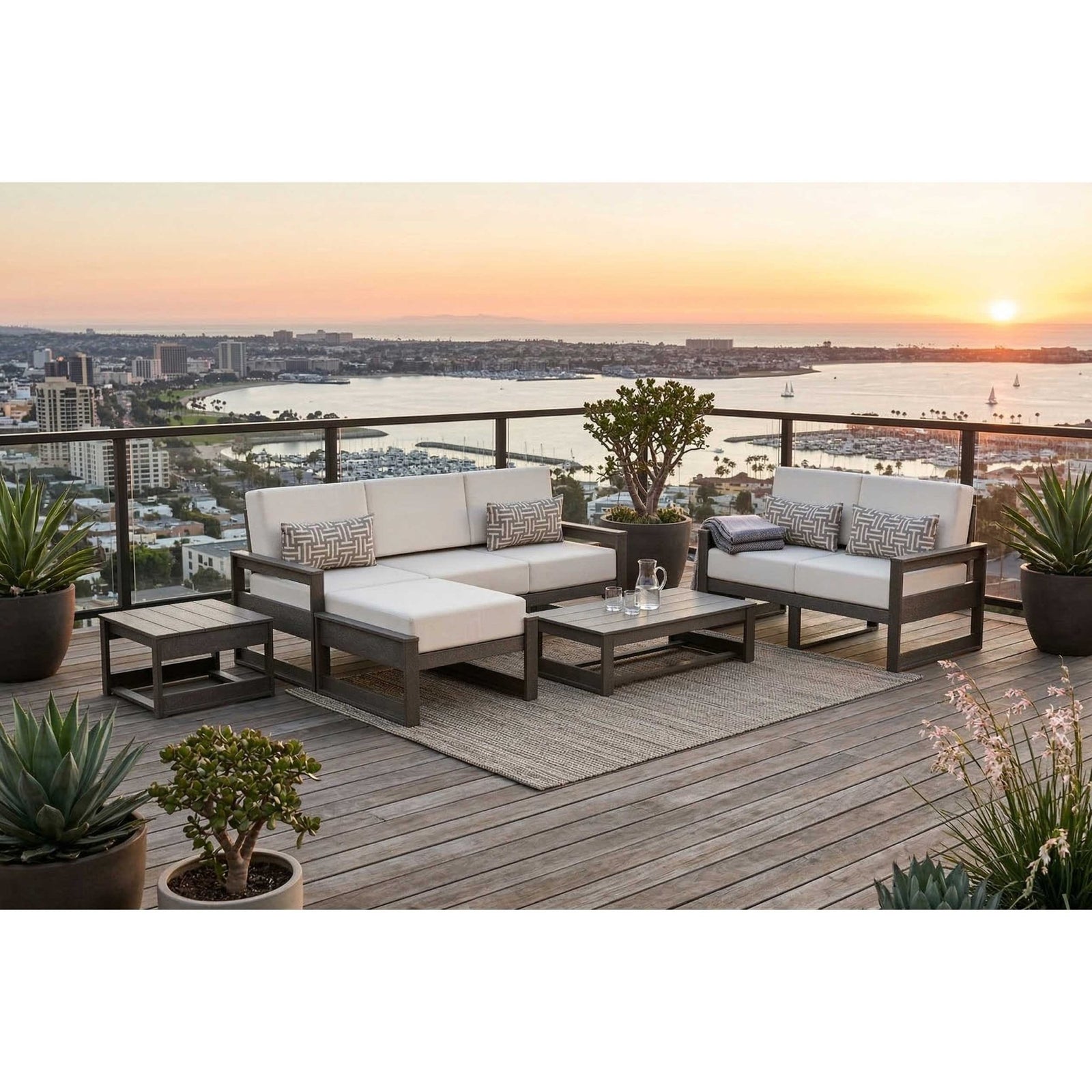 Poly patio sofa, loveseat, ottoman and tables with white cushions on a rooftop deck at sunset