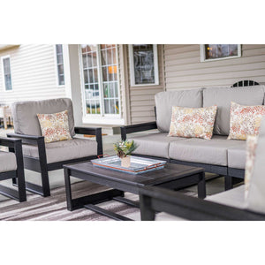 Black poly sofa and chair with gray cushions beside a coffee table holding a metal serving tray