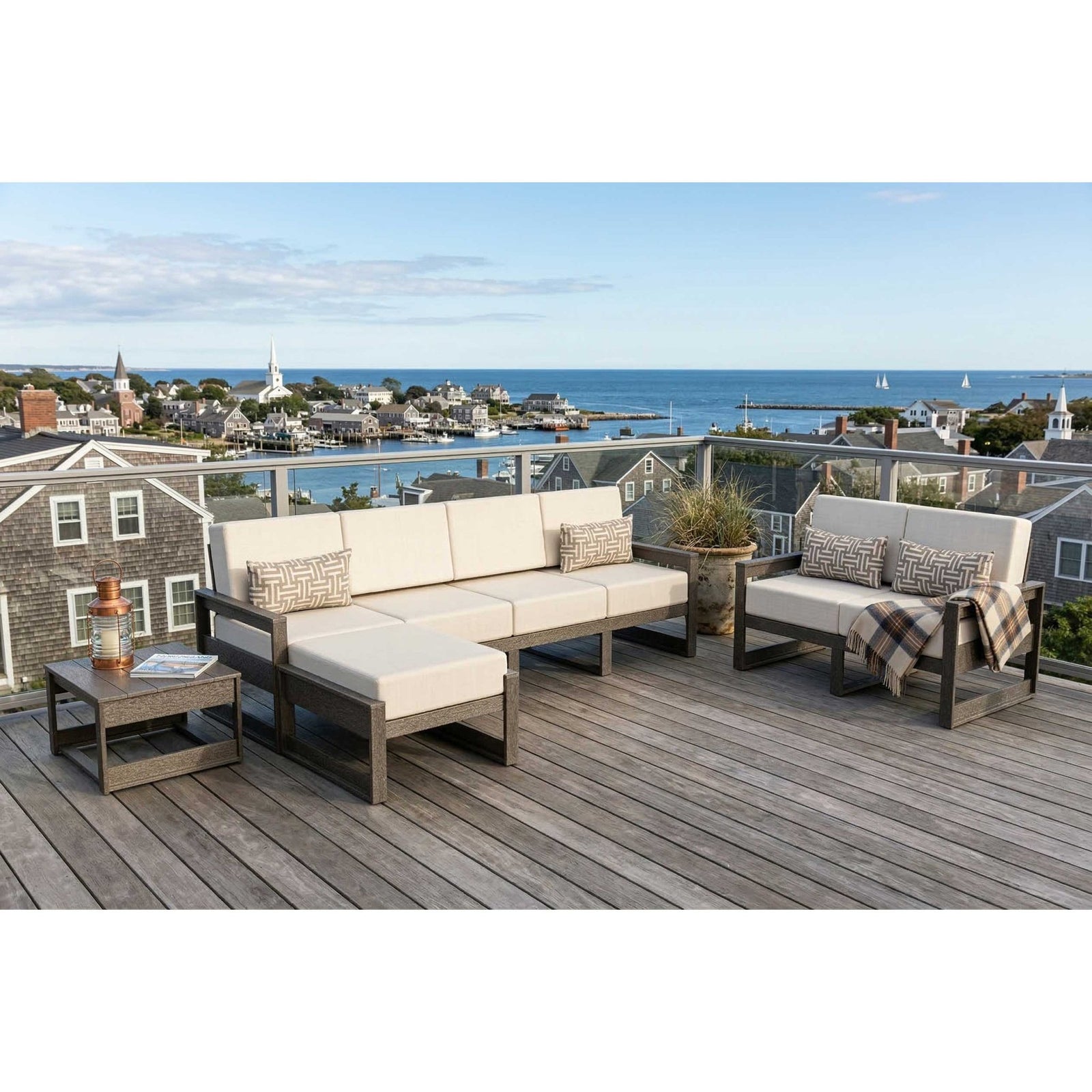 Poly patio sofa, loveseat, ottoman and side table with cream cushions on a deck above a harbor town