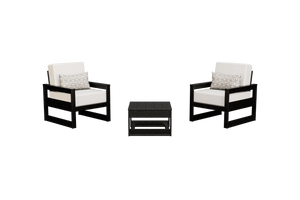 Two black poly patio club chairs with white cushions and geometric pillows flanking a square side table