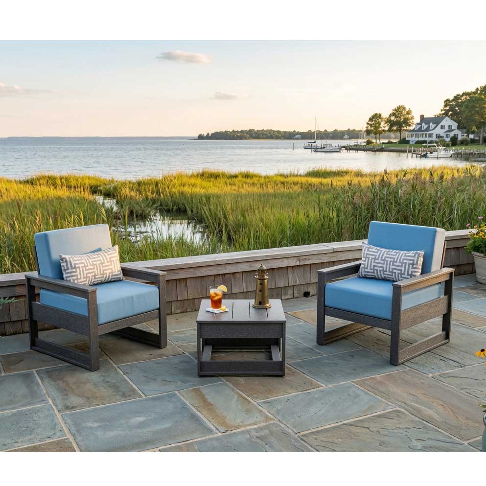 Two mid-century modern poly patio chairs with blue cushions and a square side table overlooking a marsh