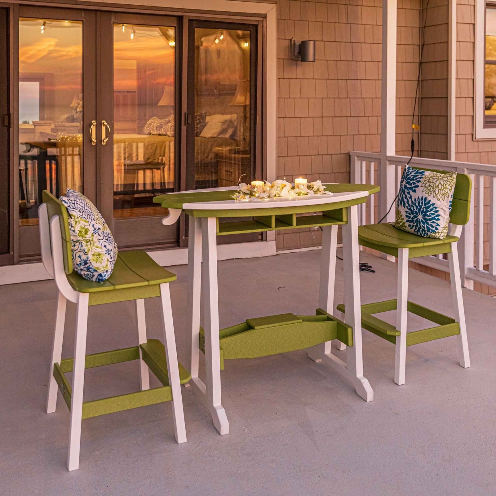 Green and white surfboard counter table set for two on a shore house porch at sunset