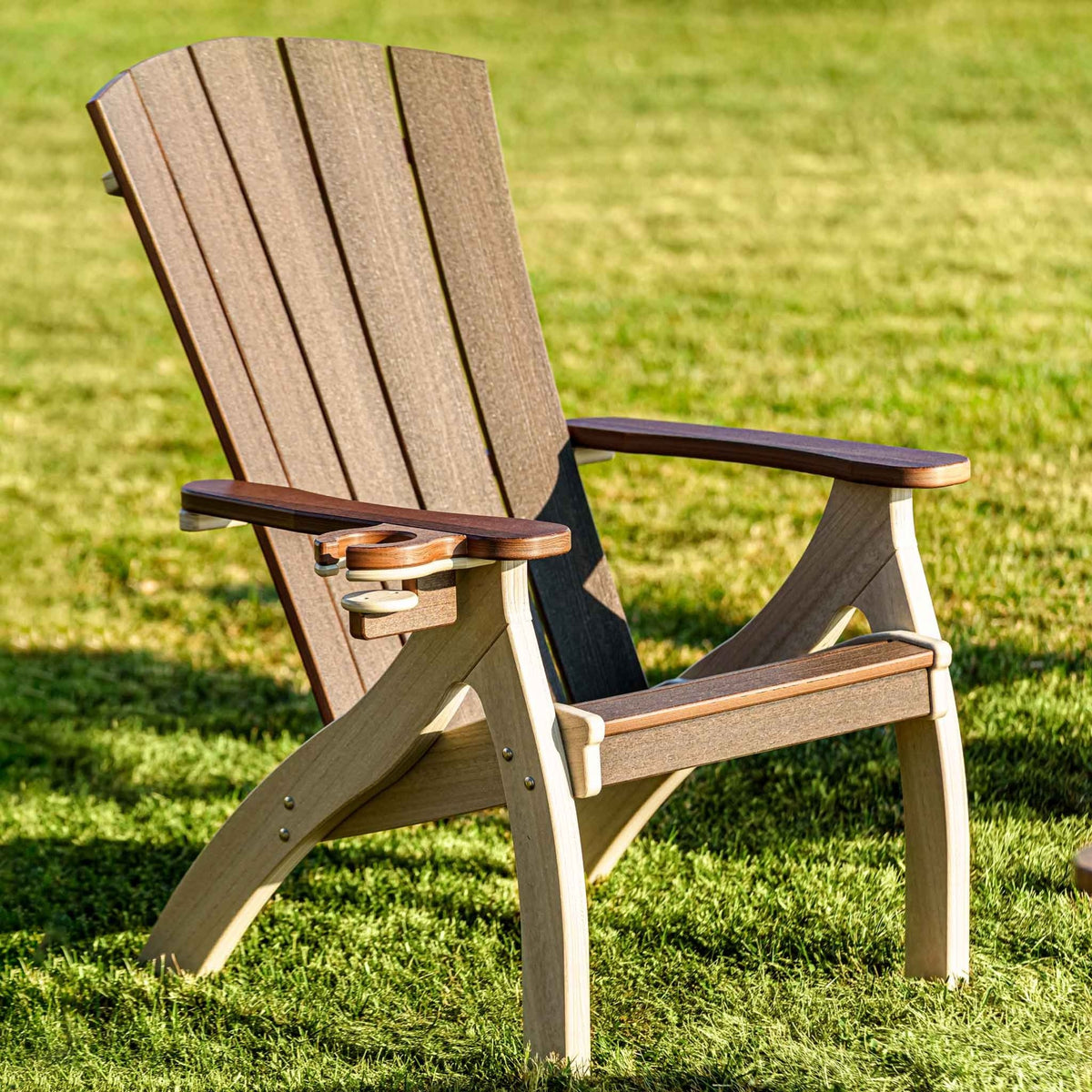 Weatherwood and brown poly siesta chair with reclined fan back, curved legs and a built-in cup holder on the arm, on grass