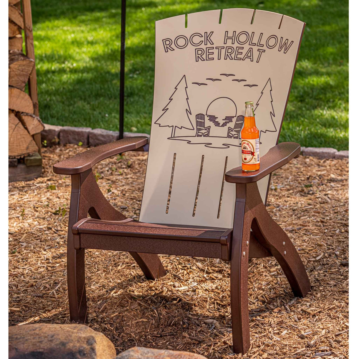 Brown and ivory Adirondack chair engraved Rock Hollow Retreat with a lake and pines scene, by a fire pit