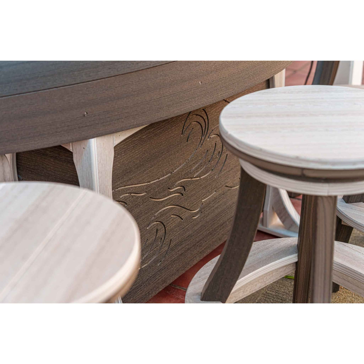 Detail of a driftwood boat bar base with carved waves beside round swivel bar stools on a patio