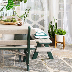 Detail of a driftwood and green poly bench with a striped pillow next to a matching picnic table on flagstone