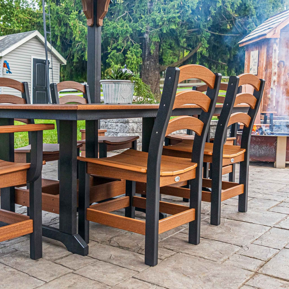 Antique mahogany and black ladder back dining chairs at a poly patio table beside a fire pit
