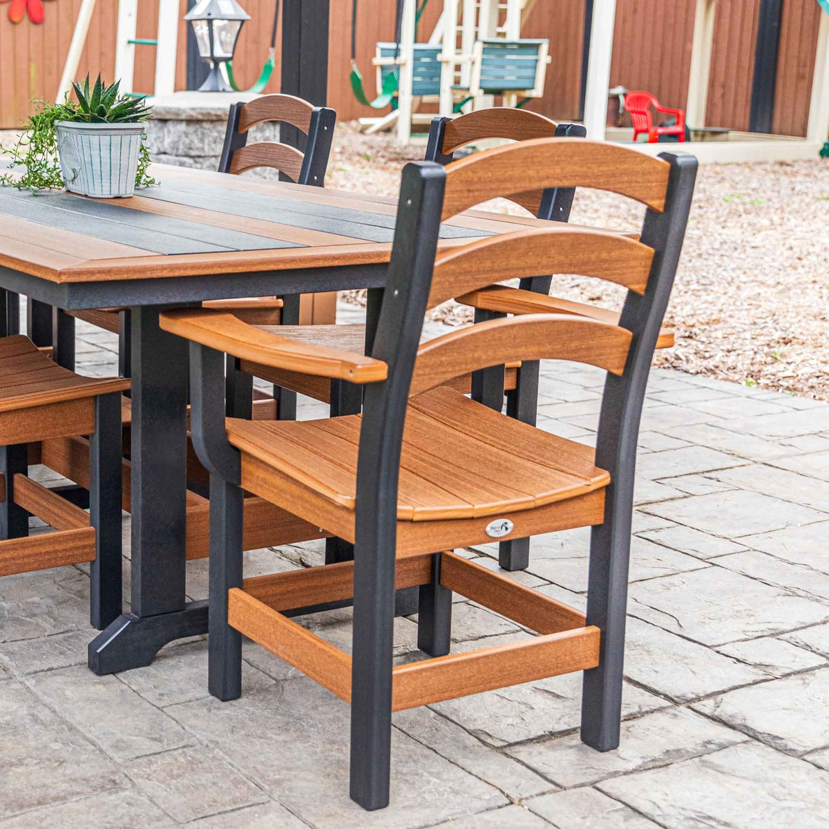 Cedar brown and black dining arm chairs at a poly patio table with a potted plant on a stone patio
