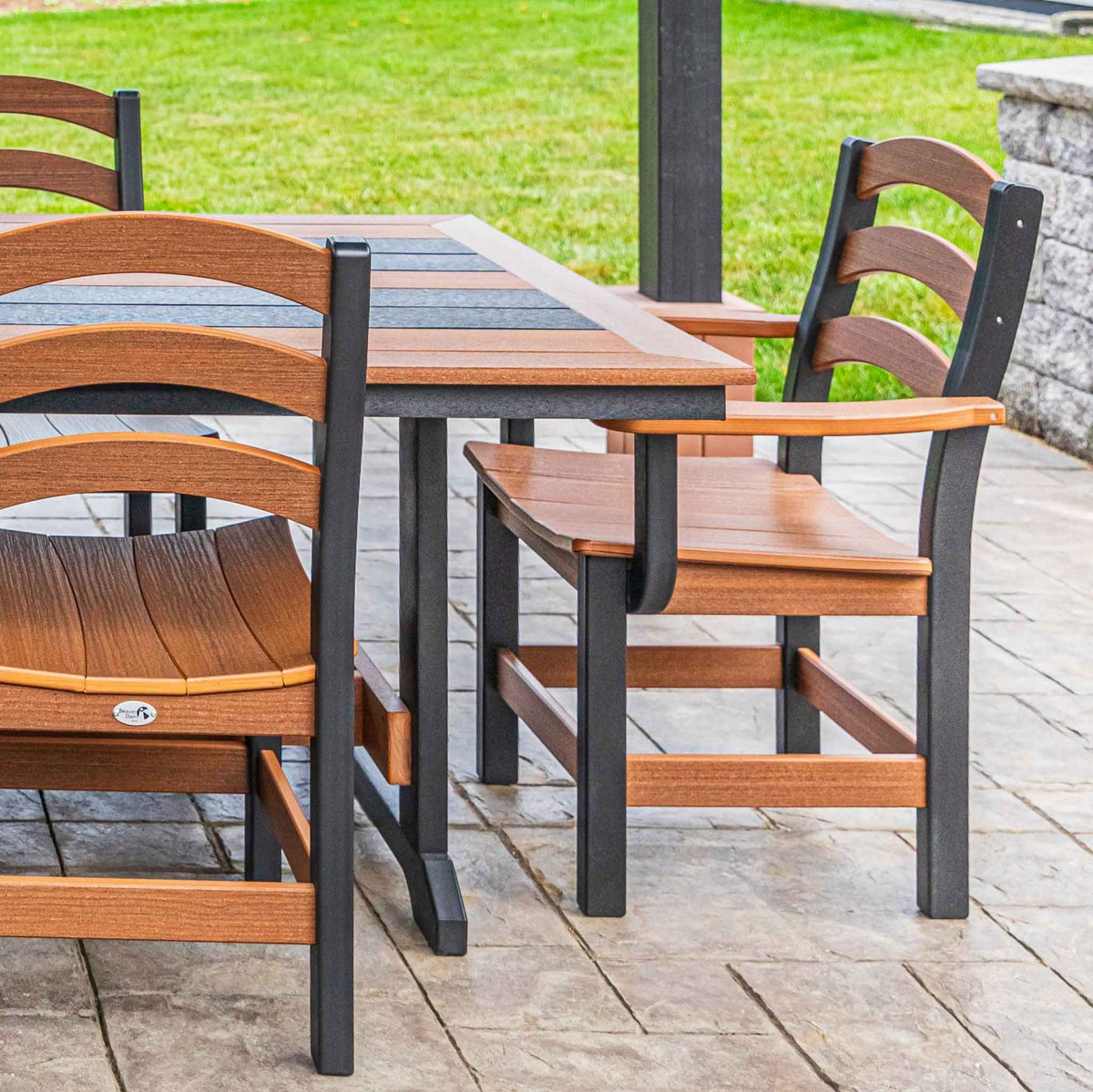 Cedar and black ladder back dining chair with arms pulled up to a poly patio dining table