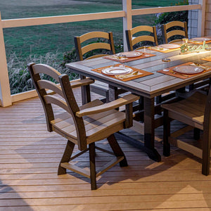 Weatherwood and black poly swivel dining chairs with arms at a set patio table on a deck at dusk