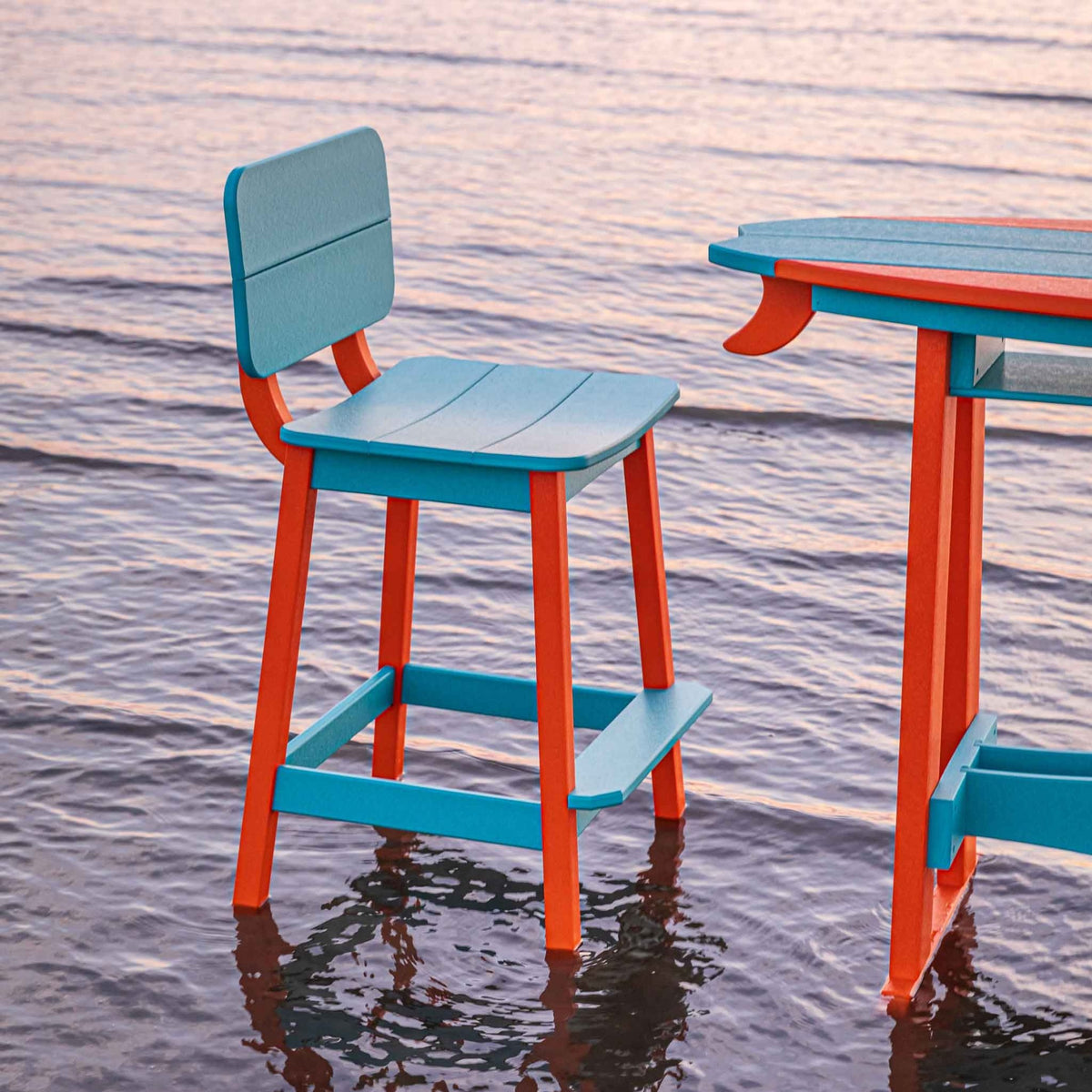 Turquoise and orange saddle bar stool with a squared back beside a matching surfboard table in the surf