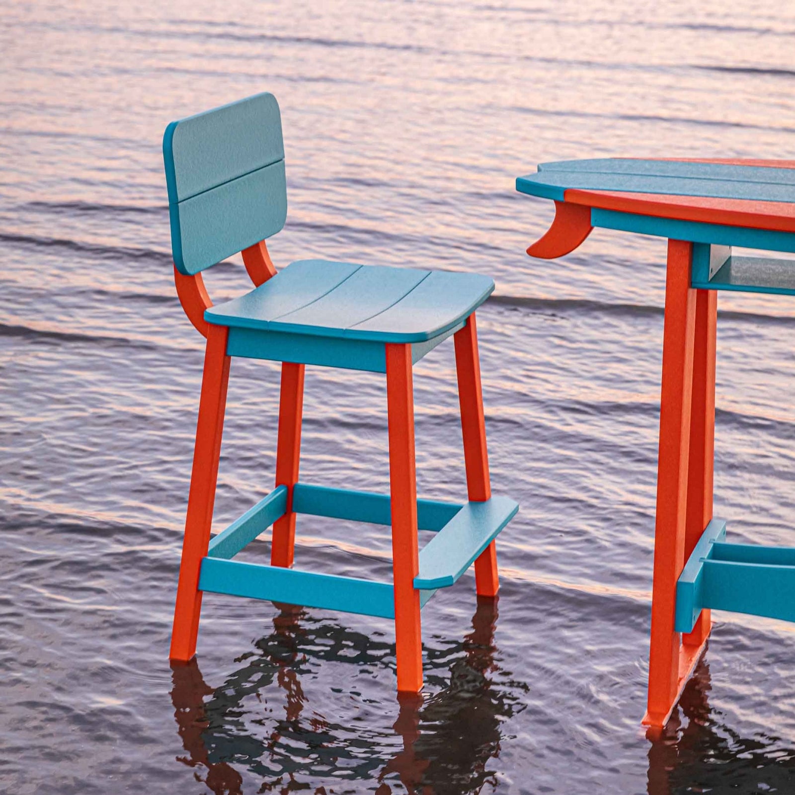 Turquoise and orange saddle bar stool with a squared back beside a matching surfboard table in the surf