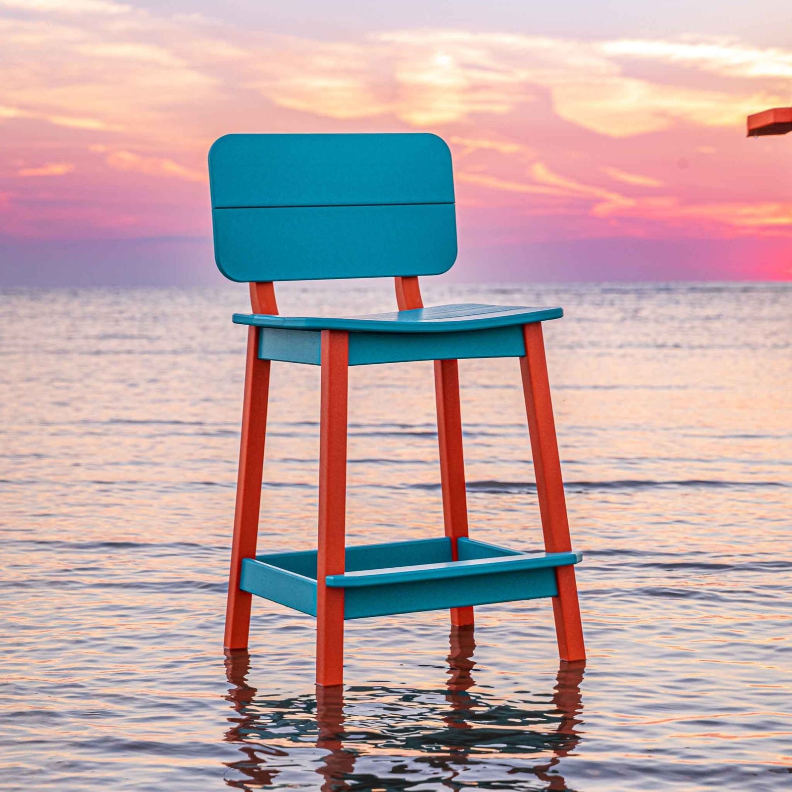 Aqua and orange counter stool with a scooped saddle seat and low back beside a poly table in the water