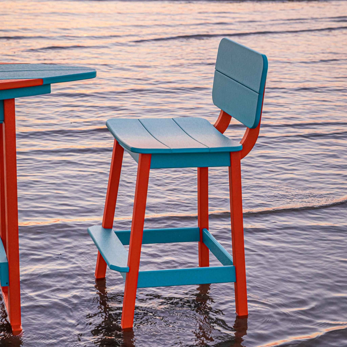 Aqua and orange counter stool with a scooped saddle seat and low back beside a poly table in the water