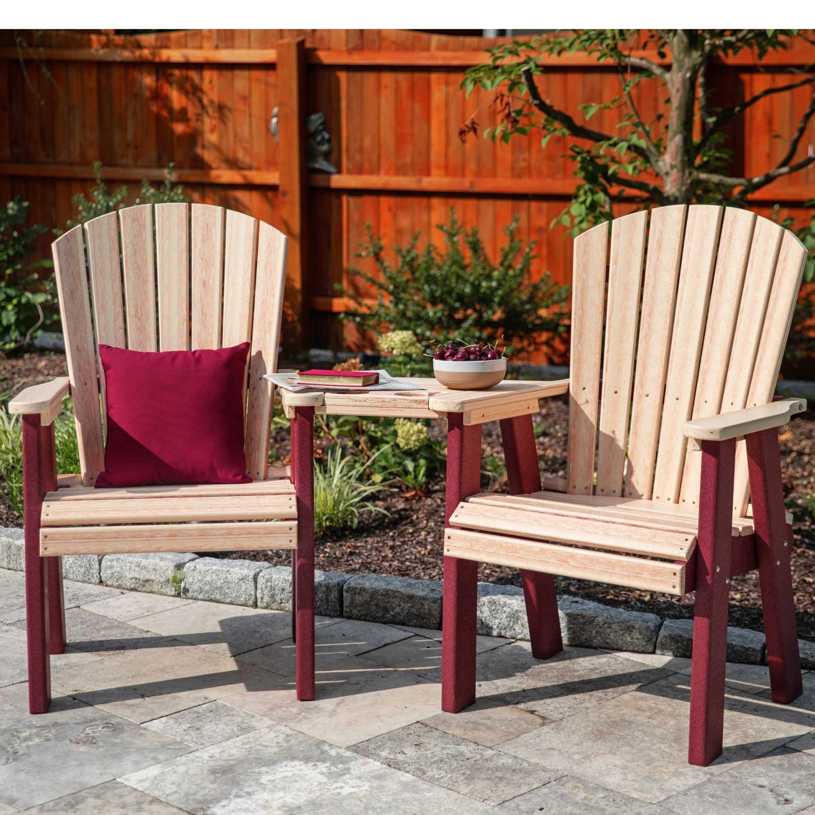Two cedar and burgundy poly upright Adirondack chairs joined by a shared corner table on a stone patio
