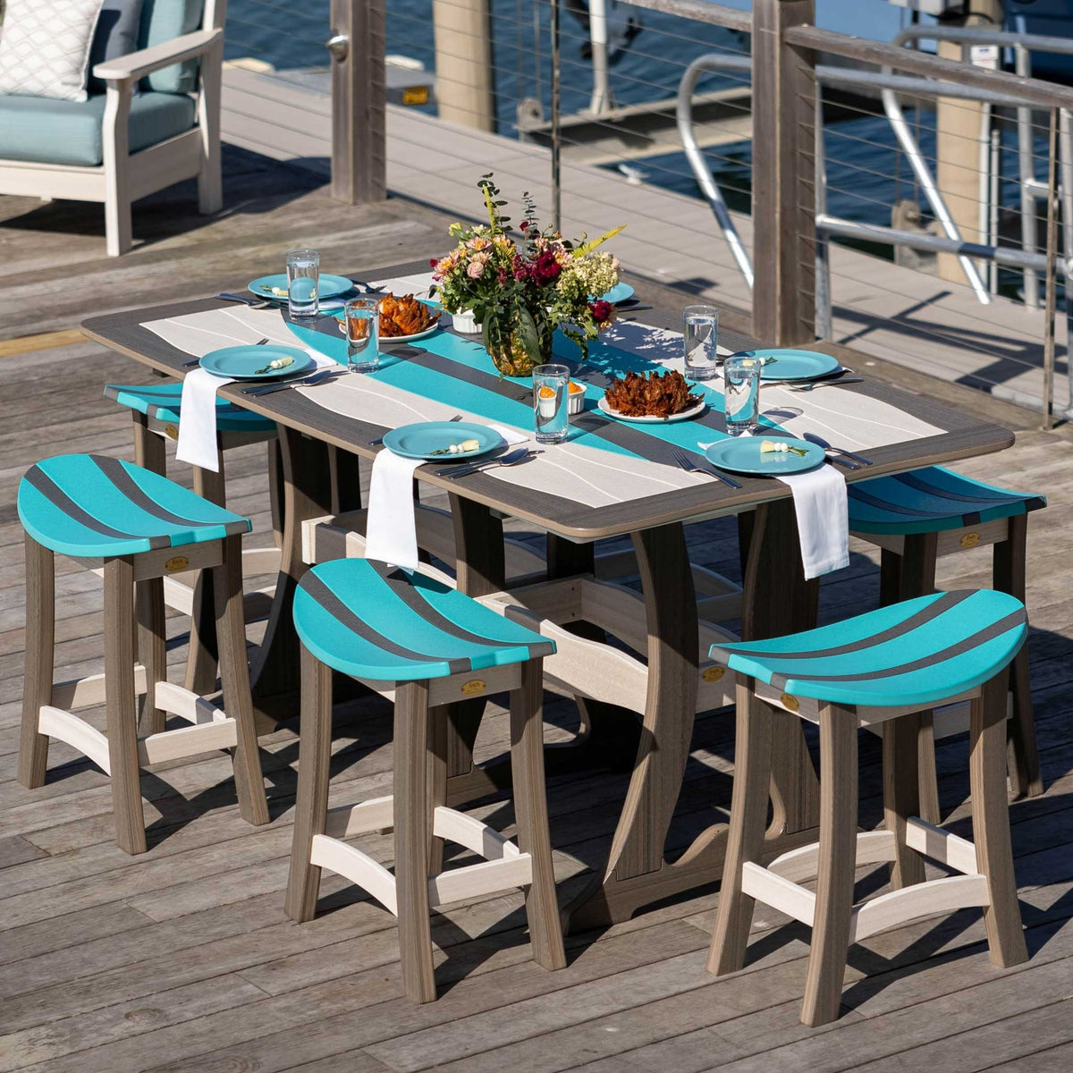 Driftwood and aruba blue surfboard counter table set with five curved saddle stools on a waterfront dock