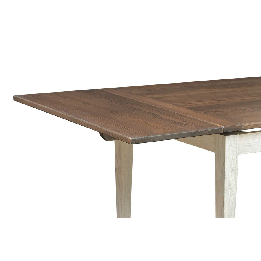Close-up of the draw leaf table's brown top sliding out over a whitewashed tapered leg