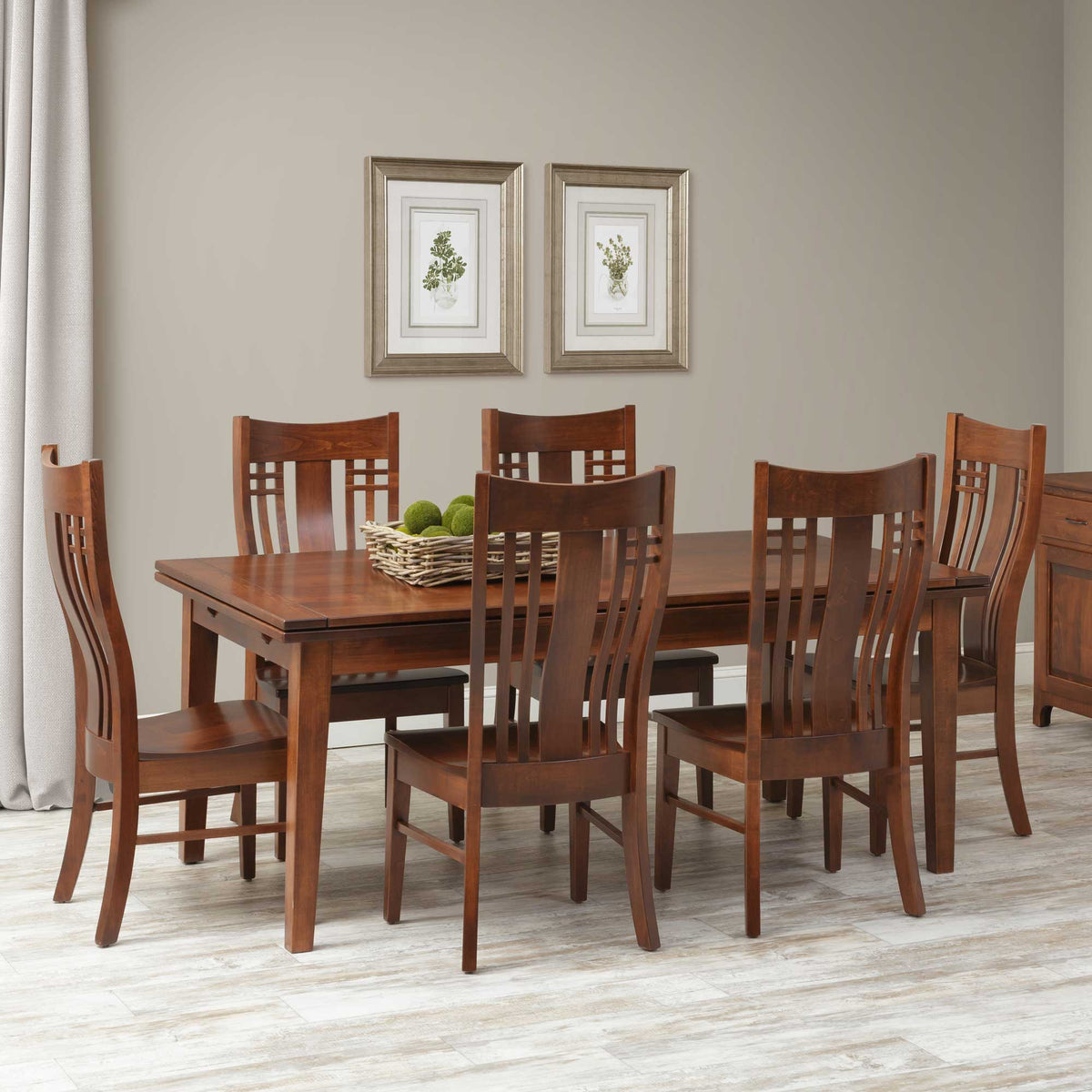 Cherry draw leaf dining table with six lattice-back chairs on light flooring beneath framed botanical prints