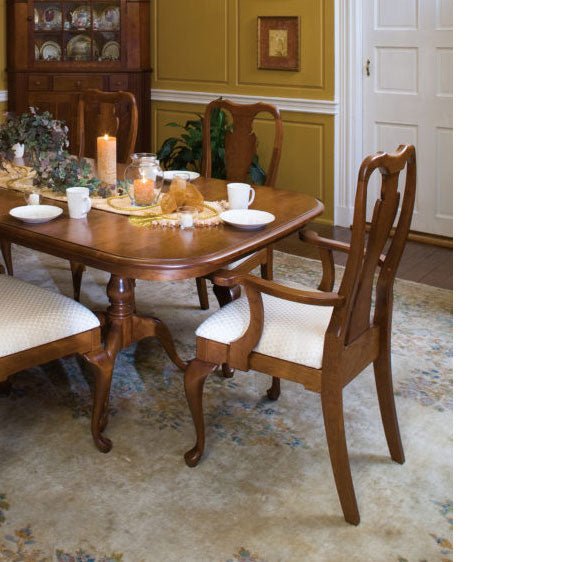 Queen Anne dining table and chairs in medium cherry set for a meal in a traditional gold walled dining room