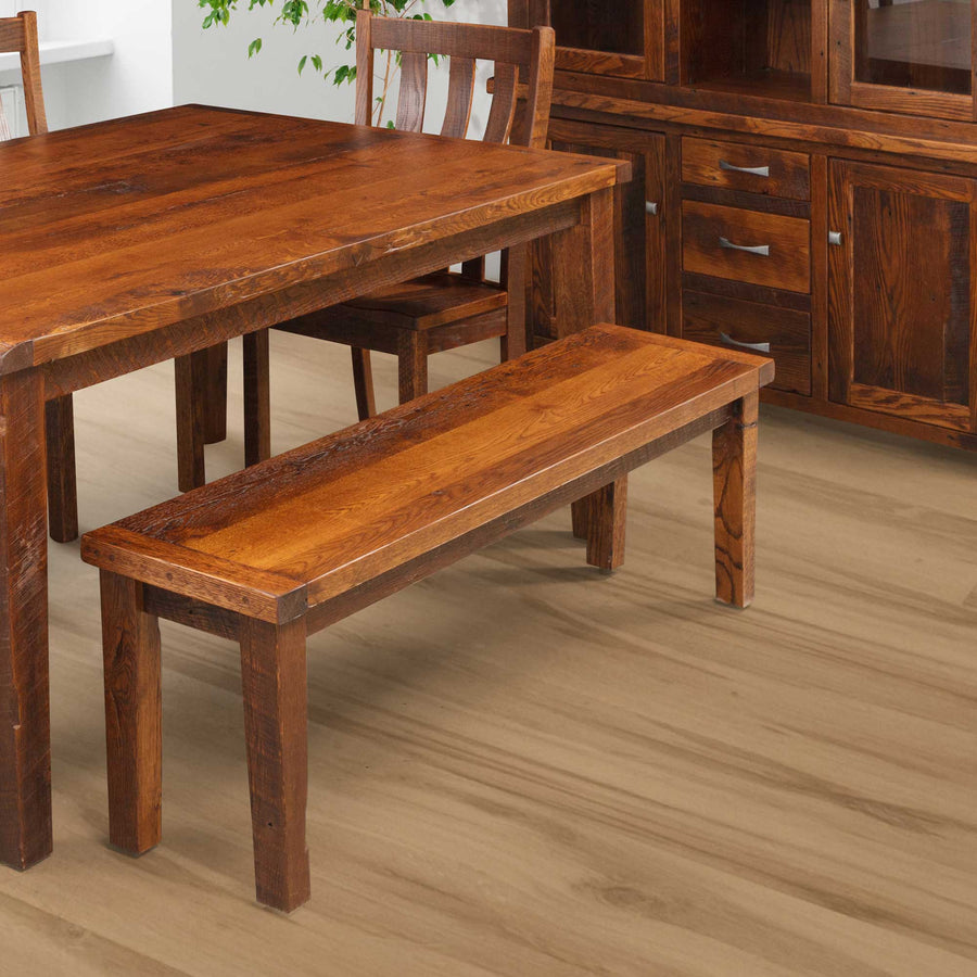 Rustic reclaimed oak dining bench in a warm medium stain, pictured beside a matching farmhouse table and sideboard buffet
