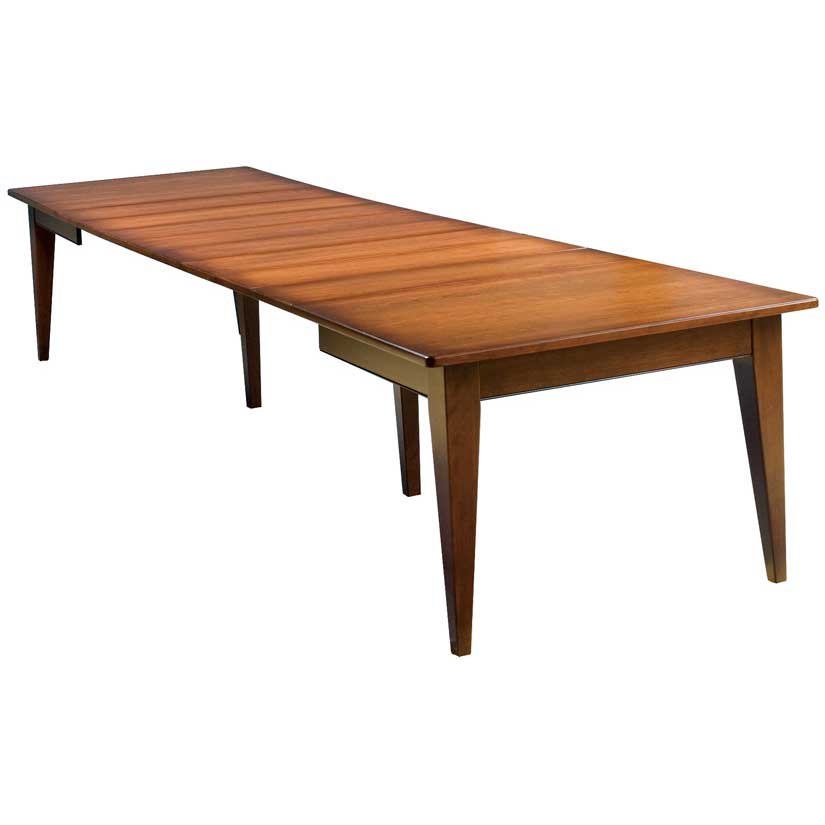 Long farmhouse extension dining table with several leaves installed and simple tapered legs, on white