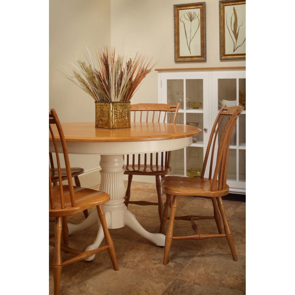 Round dining table with an oak top and reeded white painted pedestal, surrounded by oak slat back chairs