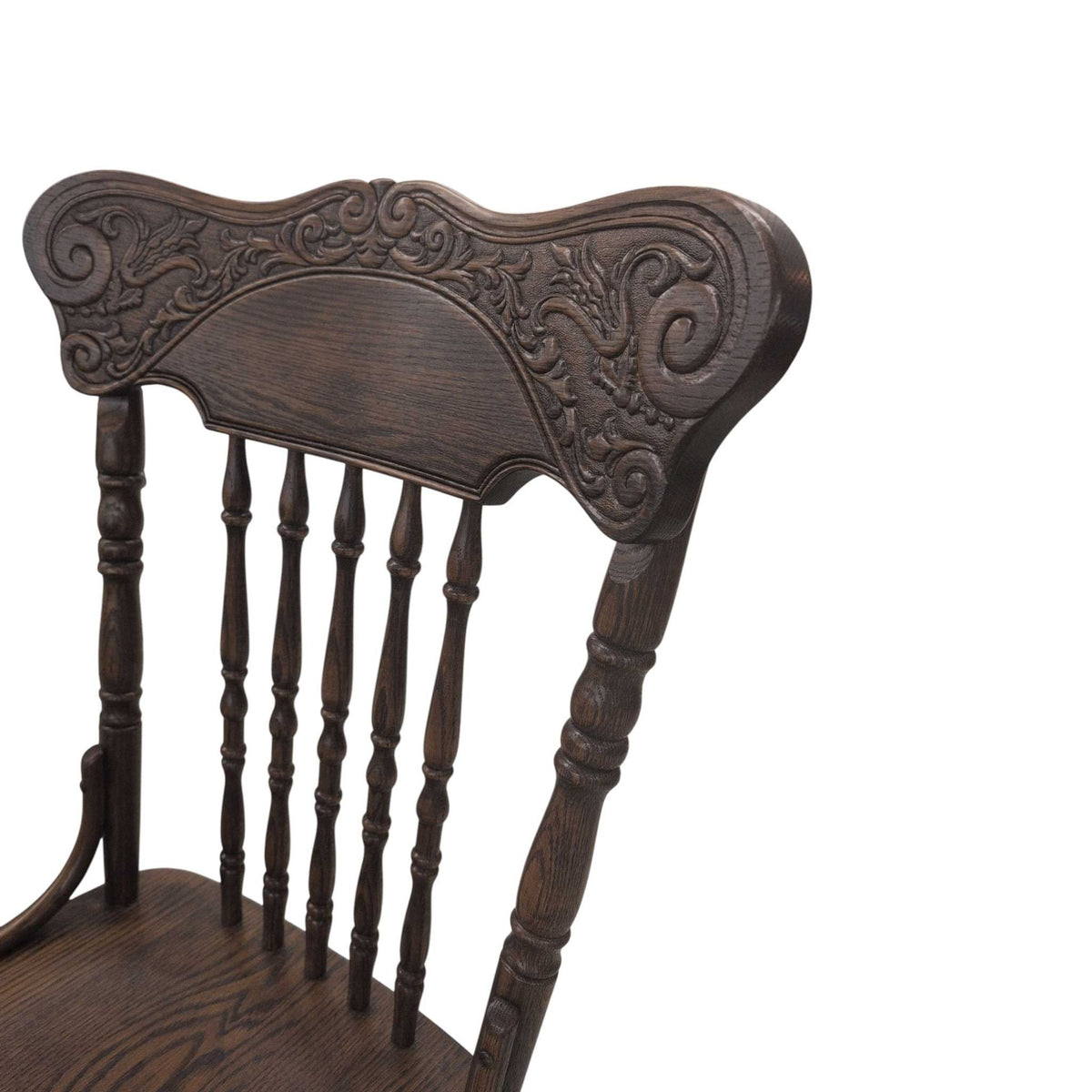 Detail of the deeply embossed floral scroll crest on a dark stained oak pressback dining chair