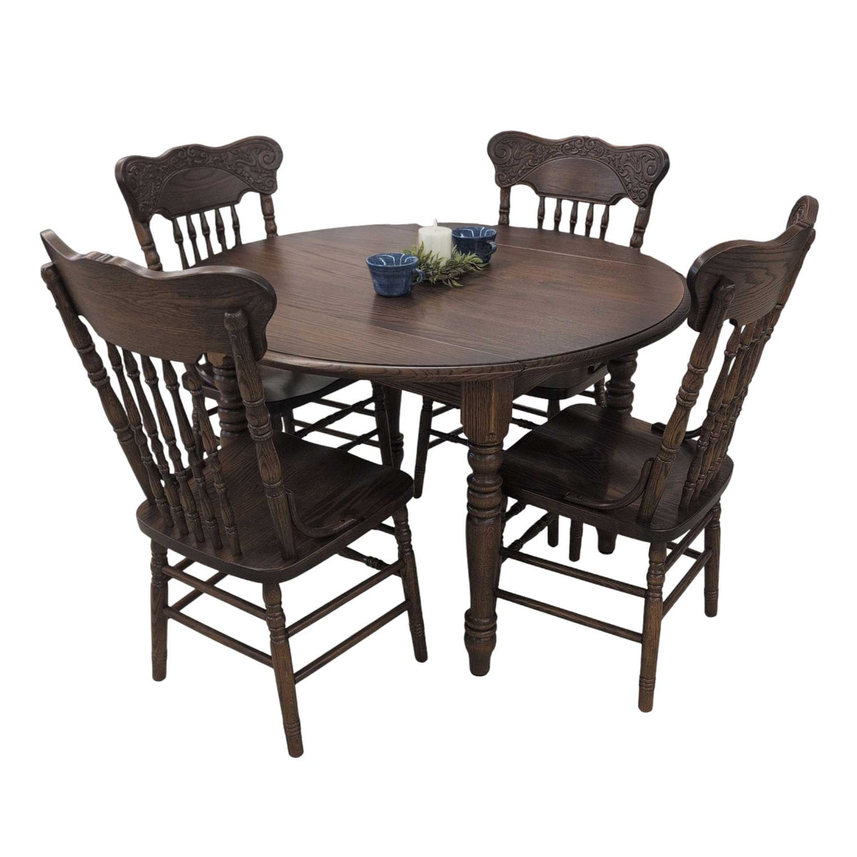 Dark stained oak round drop leaf table with four carved pressback spindle chairs, candle and blue bowls on top