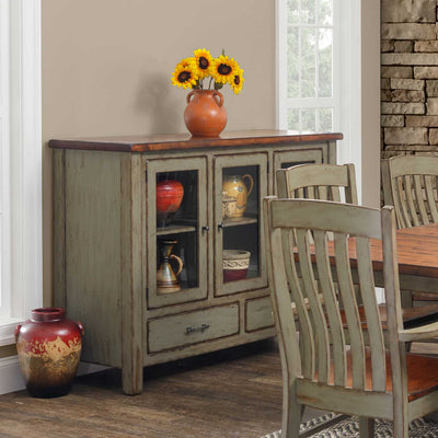 Sage green painted sideboard buffet with a butcher block top and three glass doors, styled with pottery beside a rustic dining table