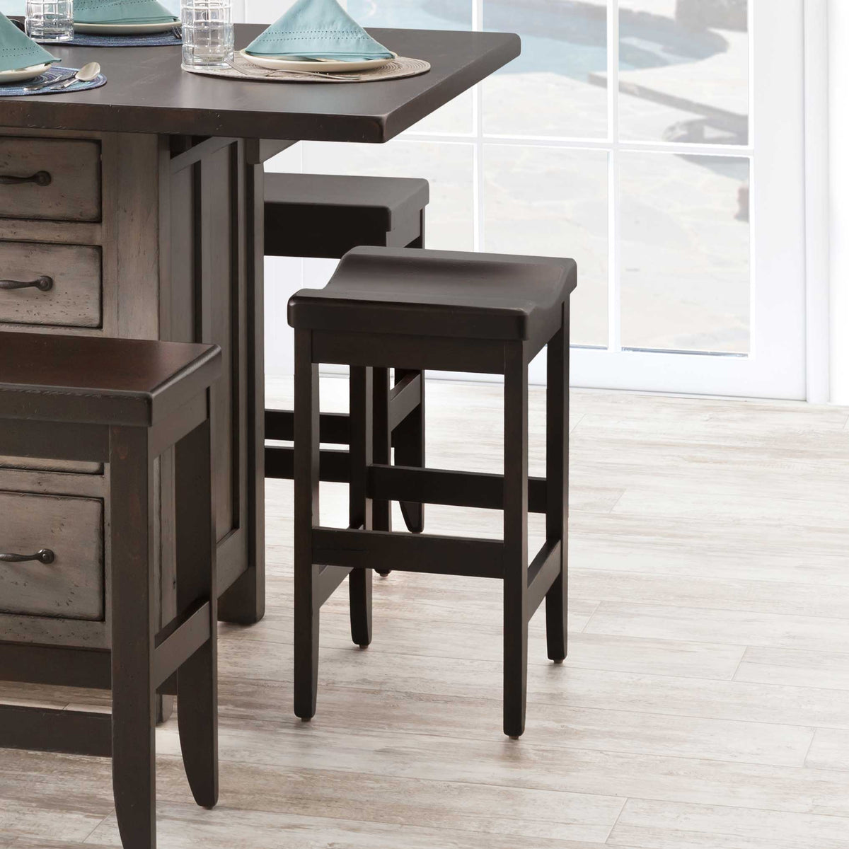 Black finished backless saddle bar stool at a gray kitchen island counter, with square legs and double footrest rungs