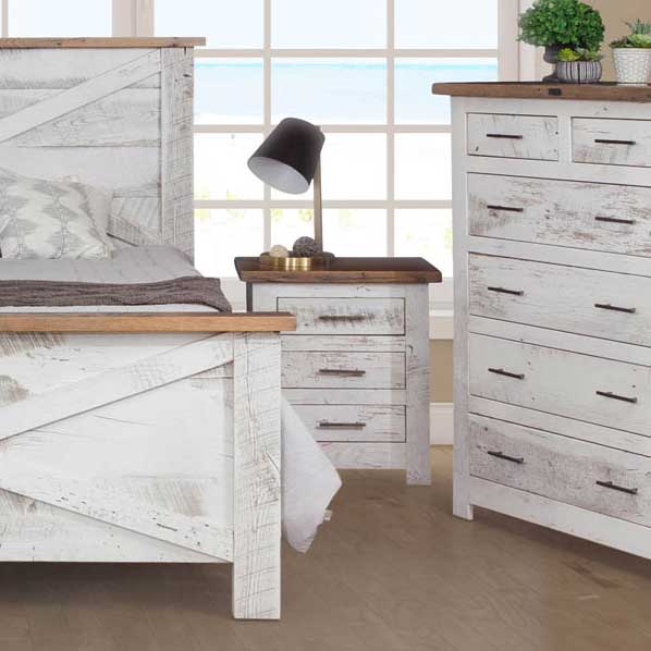 Distressed white bedroom detail with a three-drawer nightstand, natural wood top and matching tall chest of drawers
