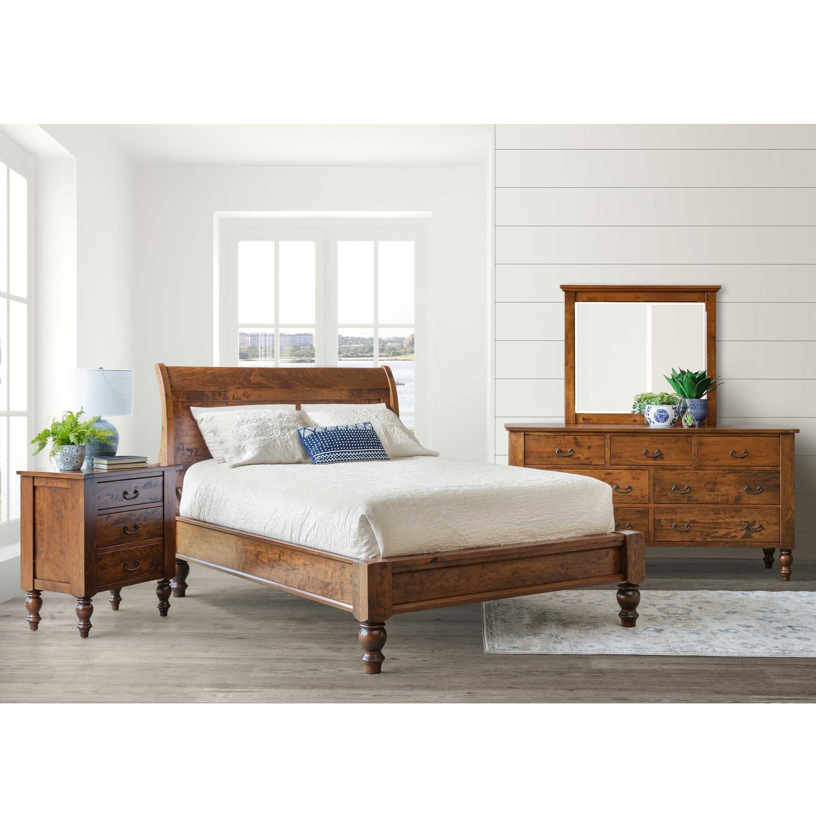 Cherry bedroom set in a coastal room with sleigh bed, nightstand and seven drawer dresser with mirror