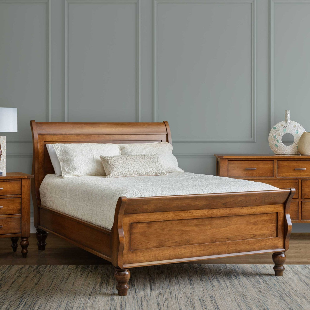 Rustic cherry sleigh bed frame viewed from the foot corner with maple slats and center support legs