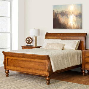 Cherry sleigh bed with scrolled headboard and footboard, turned bun feet and cream quilted bedding