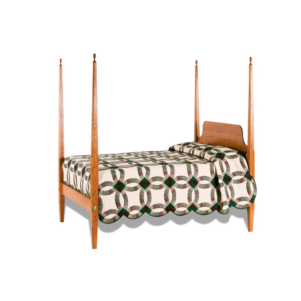Four poster pencil post bed in cherry with slim tapered posts, curved headboard and patchwork quilt