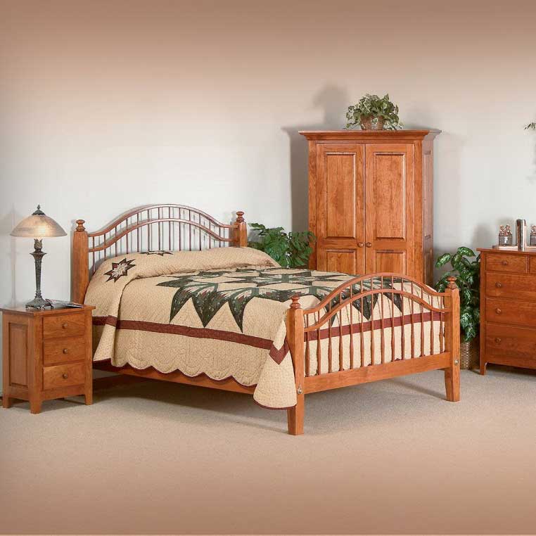 Cherry spindle bed with armoire, nightstand and chest of drawers in a neutral bedroom setting