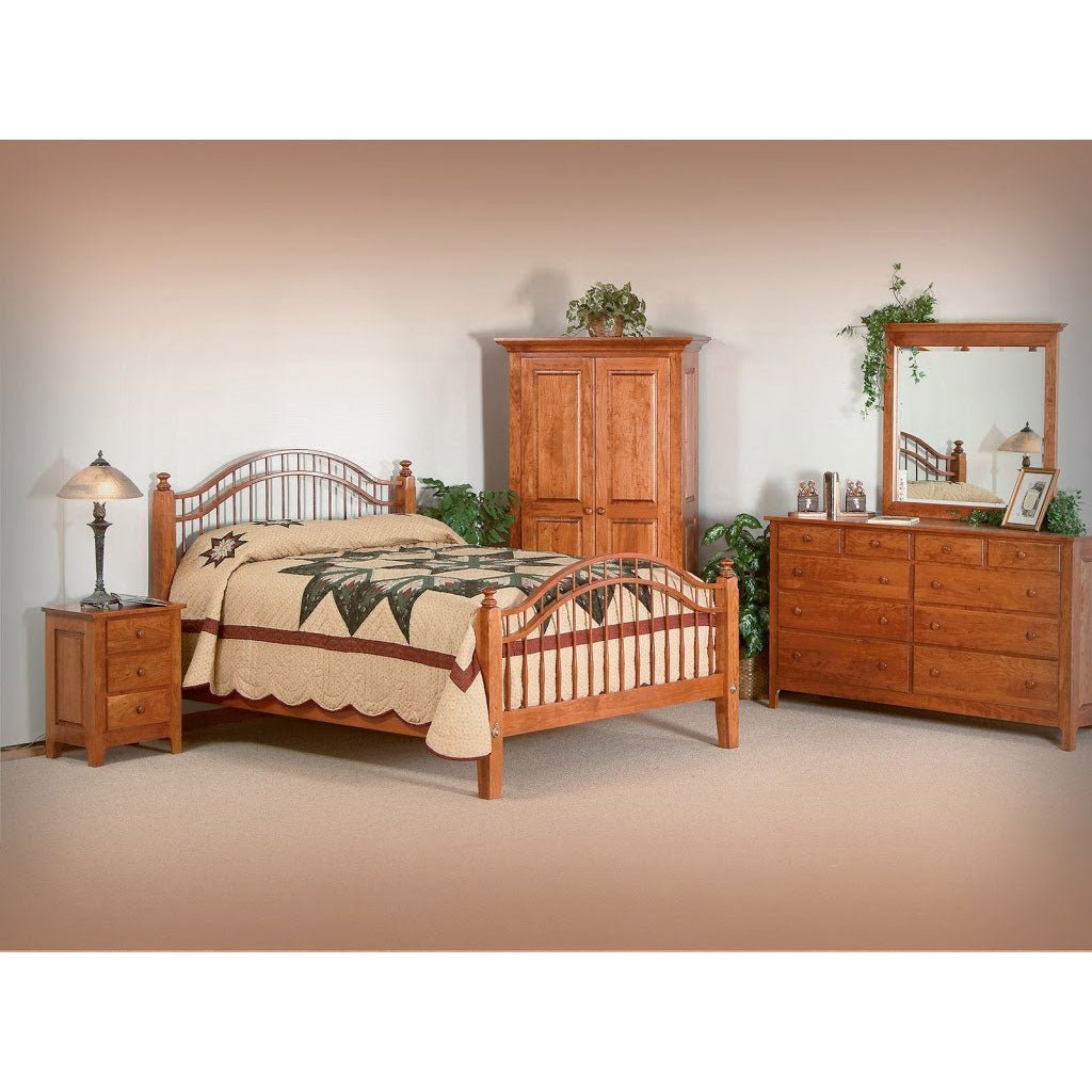 Cherry spindle bed with green pillows styled with nightstand, blanket chest, dresser and armoire