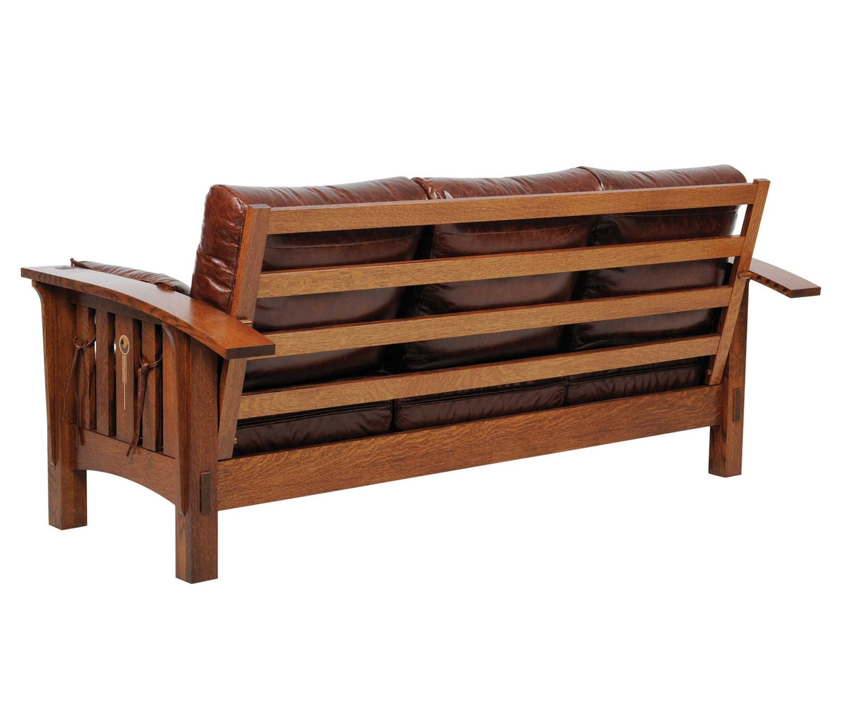 Back view of a leather mission sofa showing the oak slat back frame, wide arms and pegged joinery on white