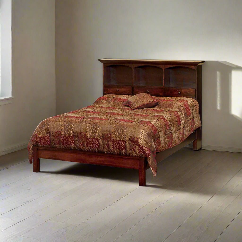 Cherry stained bookcase headboard bed with three storage cubbies and drawers in a sunlit bare room