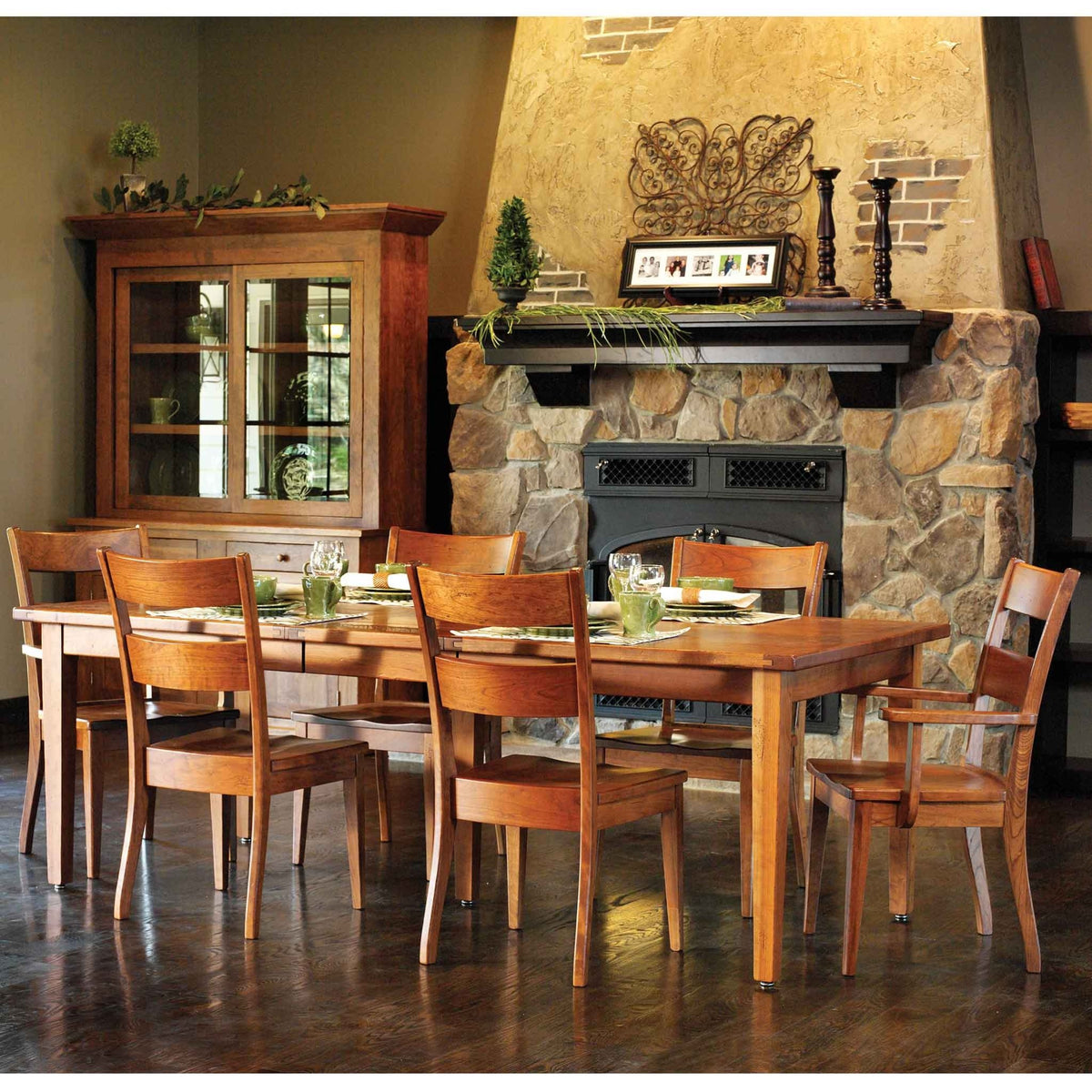 Cherry leg dining table set with six chairs, glass hutch and green place settings in a fireplace room